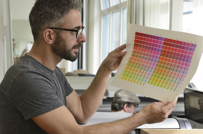 man in glasses holding up a print color chart