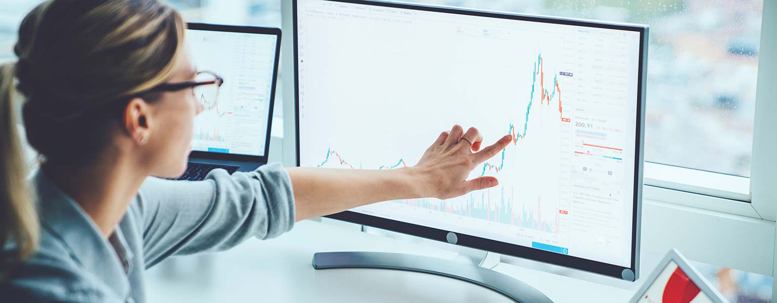enhanced_woman_computer young woman pointing at monitor with sales graph on it